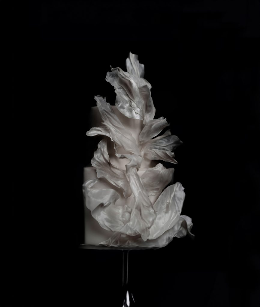 Modern wedding cake with sculpted edible petals in an artistic, high-fashion design.