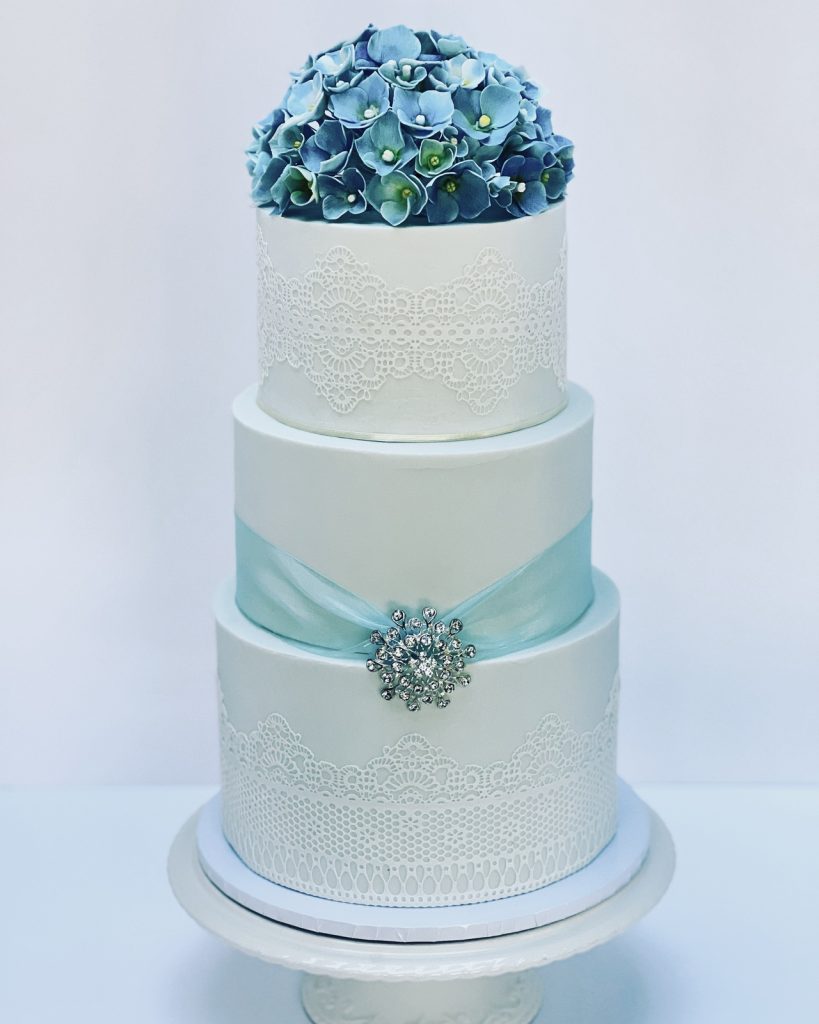 Classic vintage baby blue three-tier wedding cake topped with a full bloom of handmade hydrangea sugar flowers.