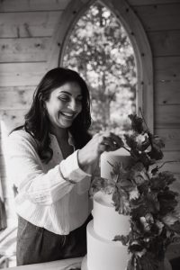 Black and white image of Dimple, owner of Sugar Creations by Dimple, carefully perfecting her luxury wedding cakes in her Leicestershire studio, East Midlands.