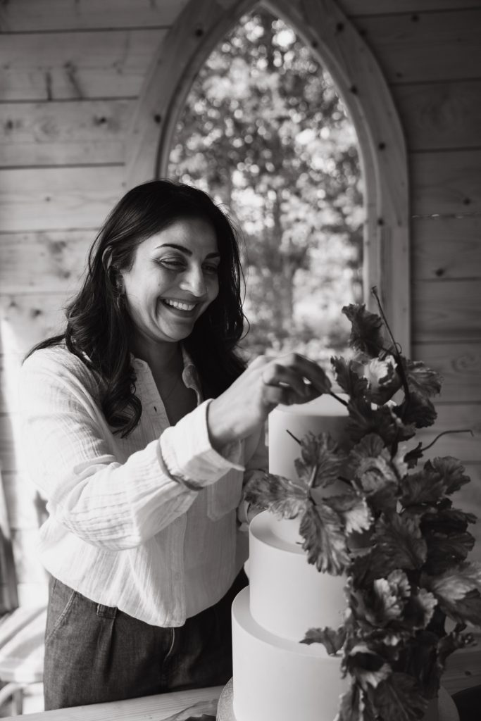 Black and white image of Dimple, owner of Sugar Creations by Dimple, carefully perfecting her luxury wedding cakes in her Leicestershire studio, East Midlands.
