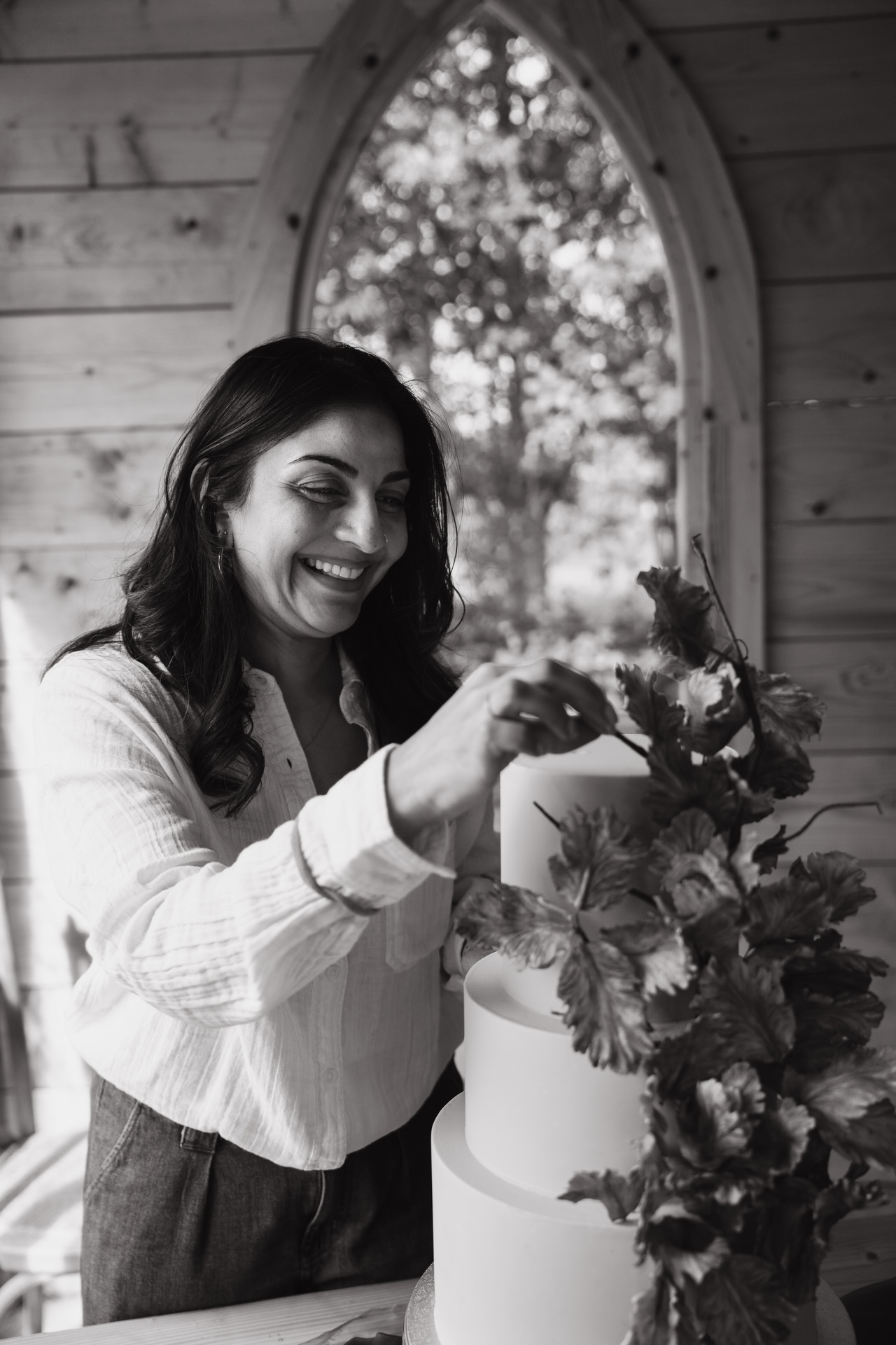 Black and white image of Dimple, owner of Sugar Creations by Dimple, carefully perfecting her luxury wedding cakes in her Leicestershire studio, East Midlands.