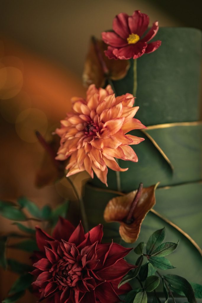 Close-up of a luxury wedding cake in rich autumn shades of green, orange, and red, handcrafted in Leicestershire for elegant East Midlands weddings.