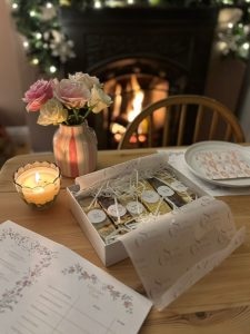 A luxury wedding cake tasting setup with six flavour samples, tasting menus and a voting card beside a cosy fireplace, created for Grace and Dan in the East Midlands.