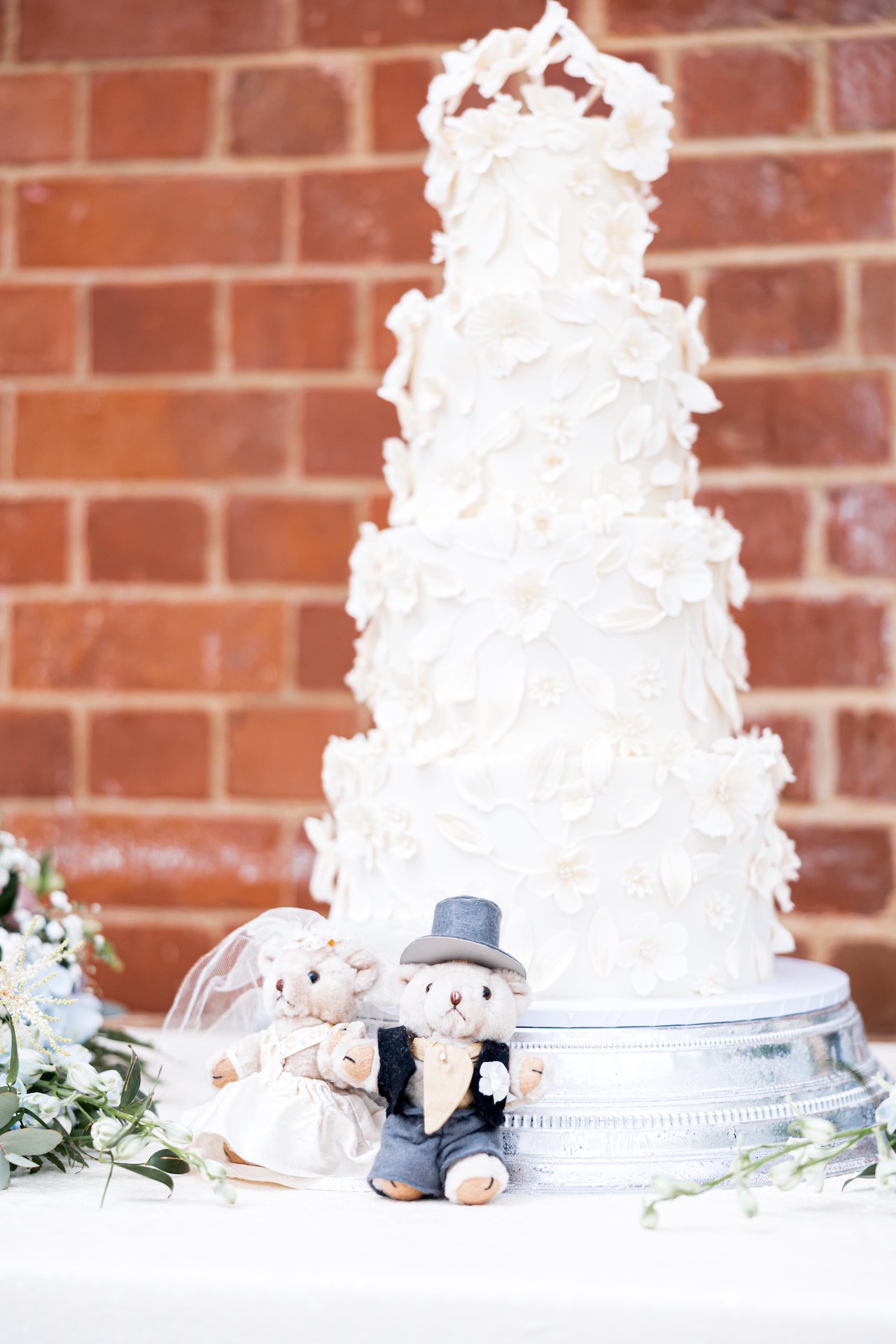 Grace and Dan’s luxury wedding cake at Kilworth House with the sentimental teddy bears from the bride’s parents' 1995 wedding placed in front.