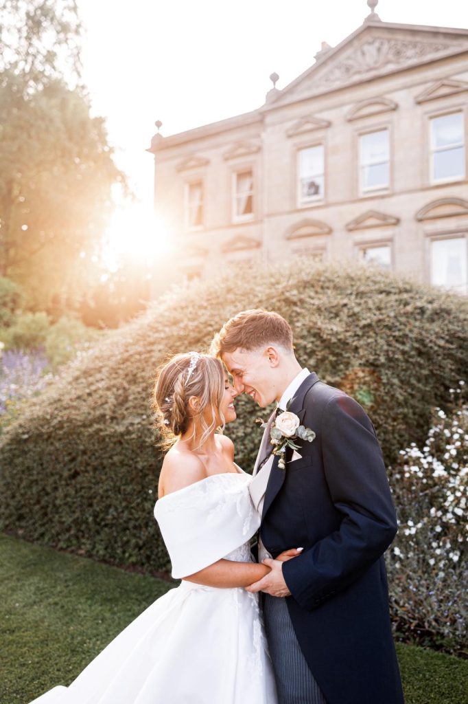 Grace and Dan standing lovingly together in front of Kilworth House in Leicestershire on their wedding day.