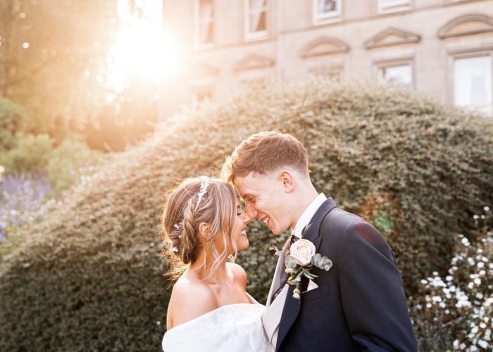 Grace and Dan standing lovingly together in front of Kilworth House in Leicestershire on their wedding day.
